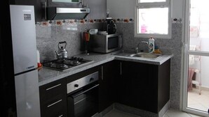 Una cocina moderna con refrigerador, estufa, microondas y ventana.