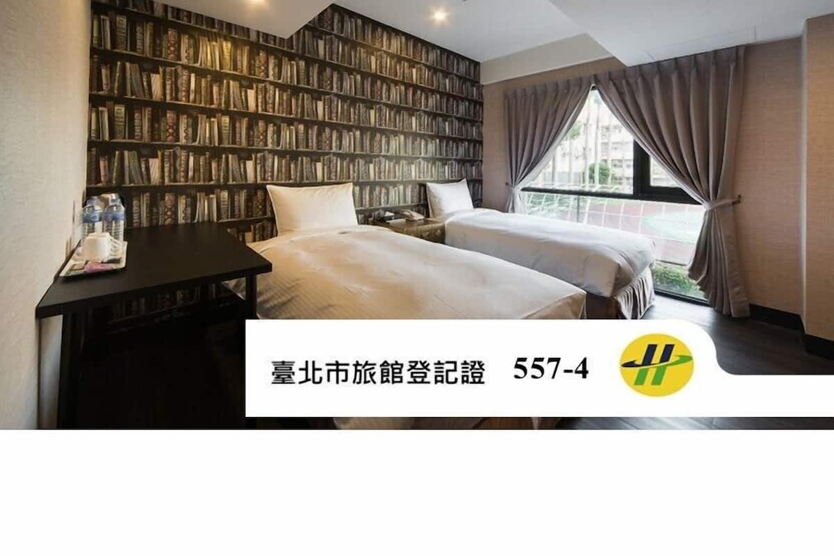 A hotel room with two beds, a bookshelf, a desk, and a window with curtains.