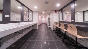 Un baño largo y moderno con varios lavamanos, espejos y zonas de estar.