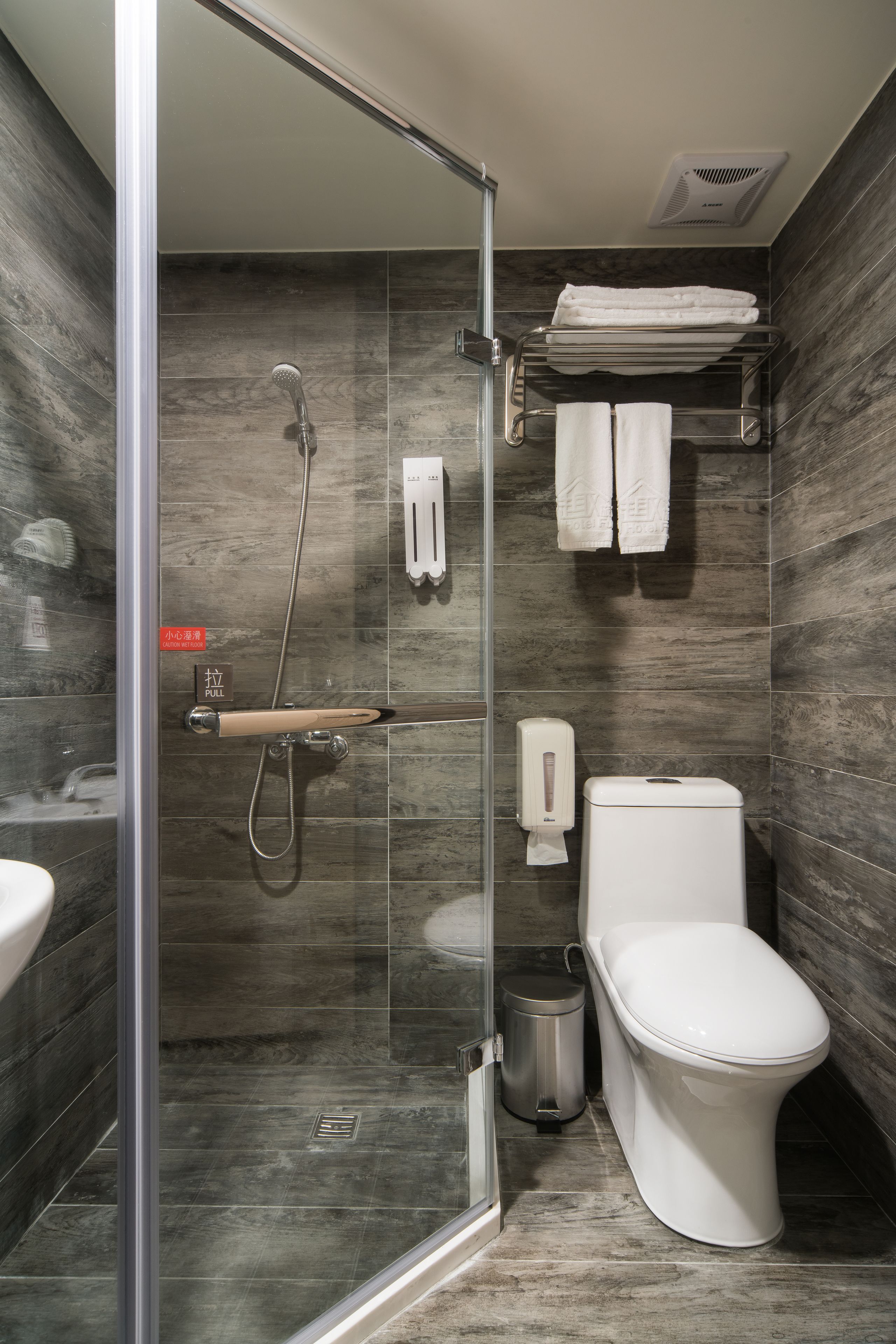 A modern bathroom with a glass-enclosed shower, a toilet, and a sink.