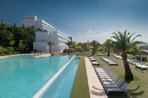 Ett hotell med en swimmingpool, solstolar och palmer.