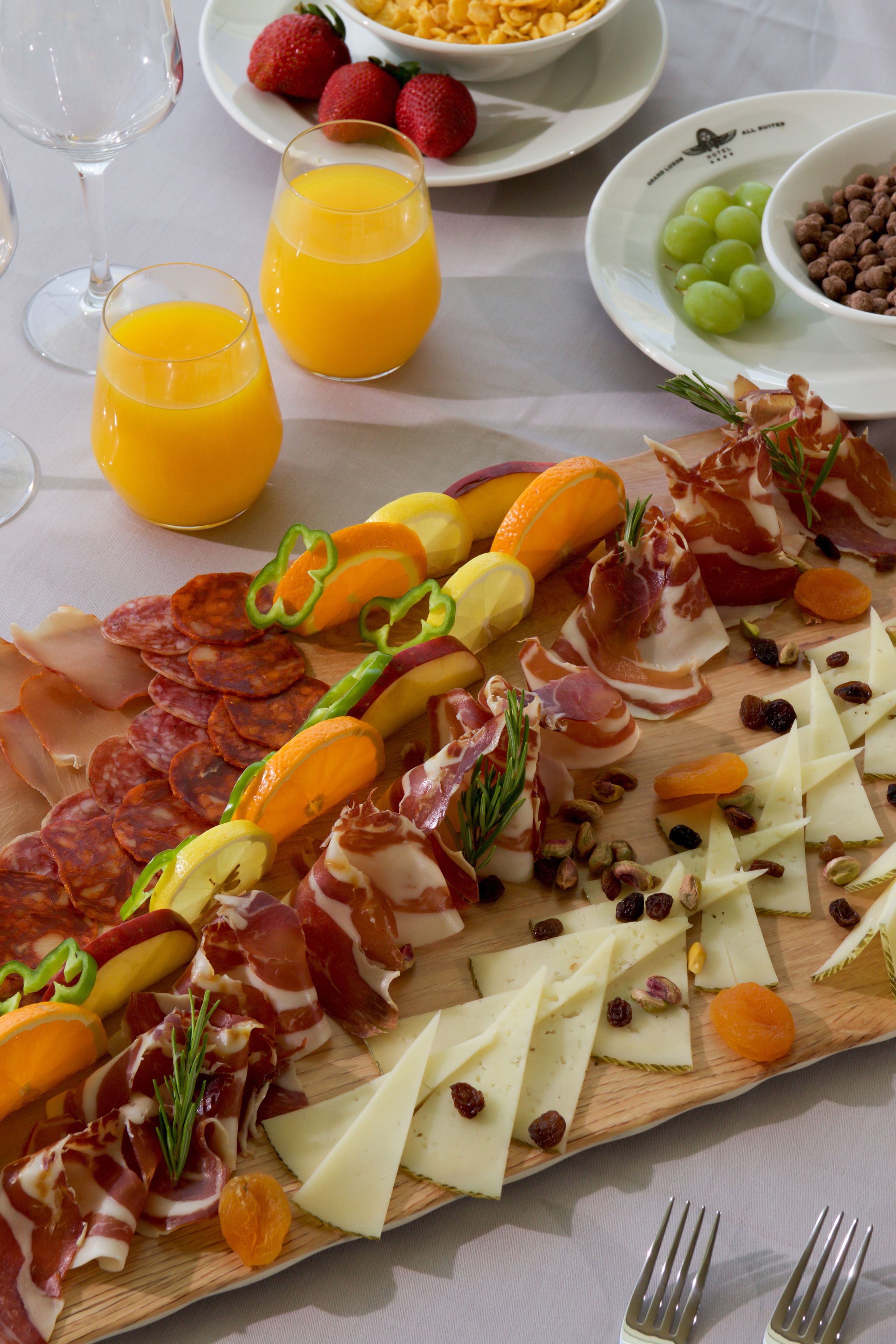 A charcuterie board with various meats, cheeses, and fruits.