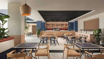 Una cafetería moderna con varias zonas de estar, una barra y una gran variedad de plantas.