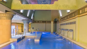 An indoor swimming pool with clear water, multiple entry points, and a ceiling with star projections.