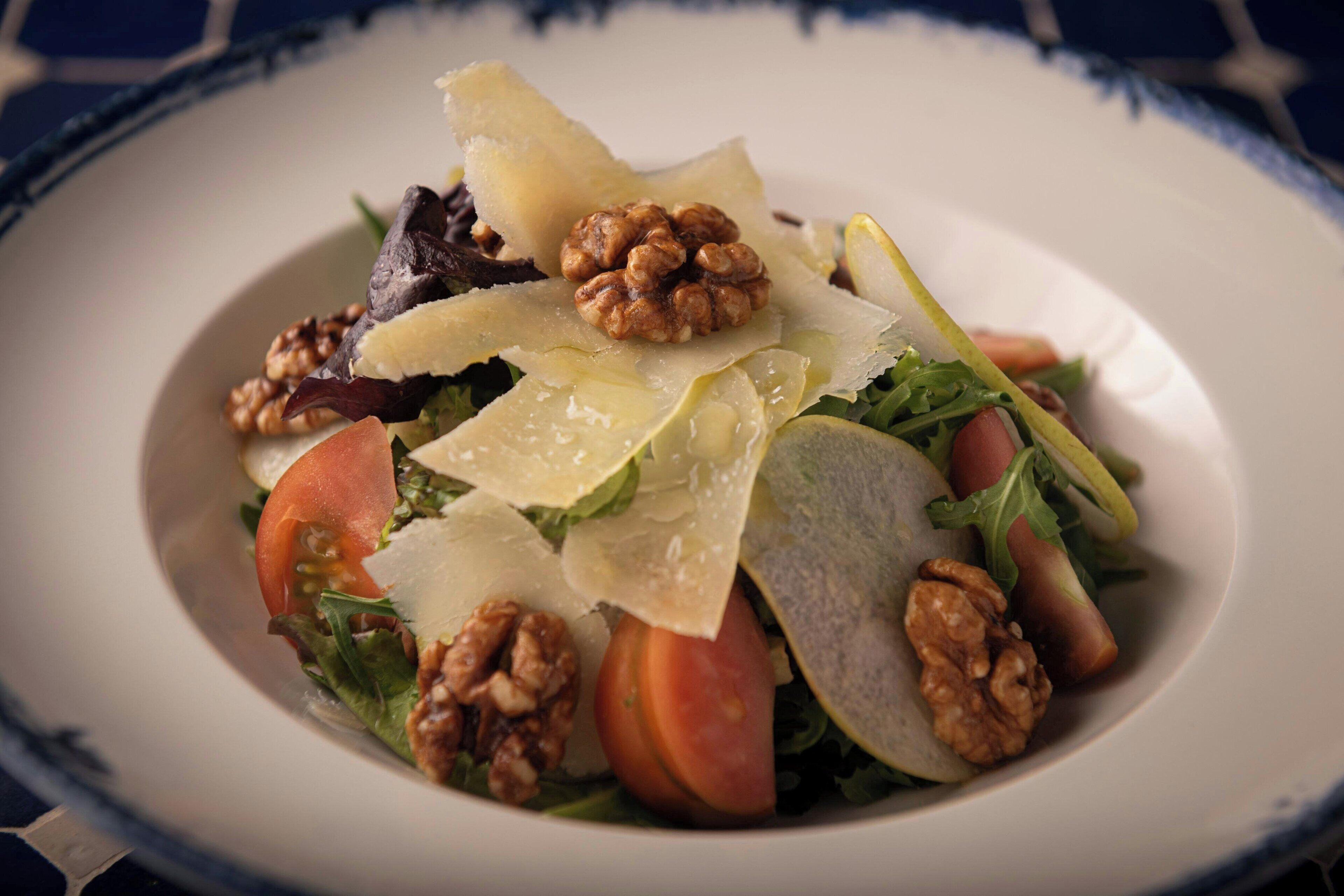 Ensalada con nueces, queso y hojas verdes en un plato.