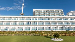 Un hotel moderno con una torre central, varios balcones y un césped bien cuidado.