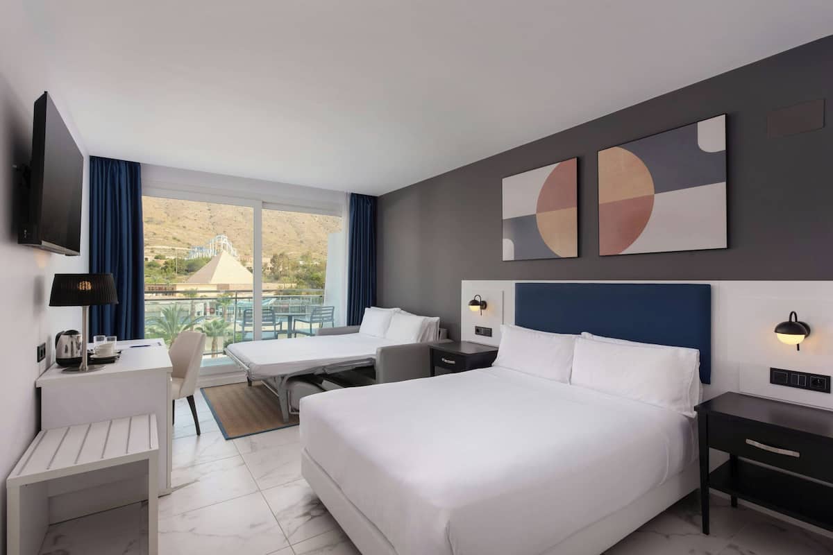 Una habitación de hotel con cama, escritorio, silla y televisor.
