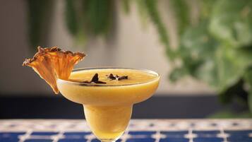 A cocktail in a martini glass with a decorative garnish on a tiled table.