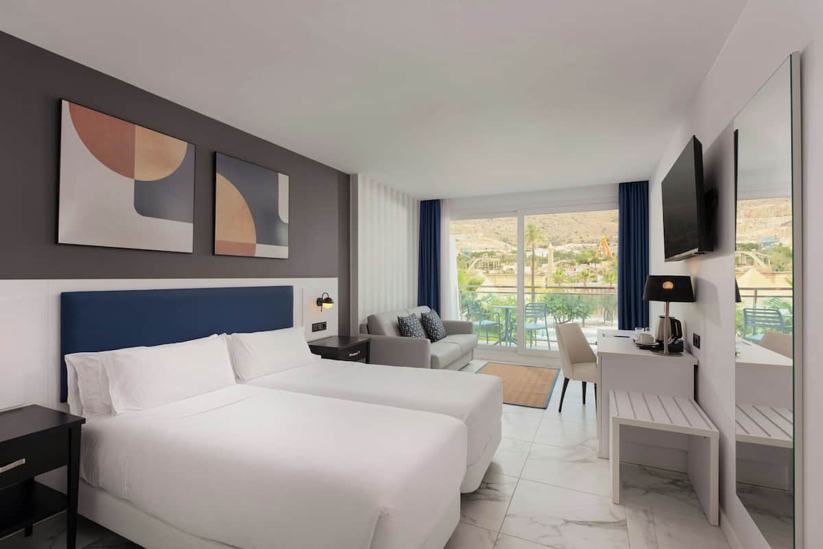 Una habitación de hotel con cama, escritorio, silla y televisión.