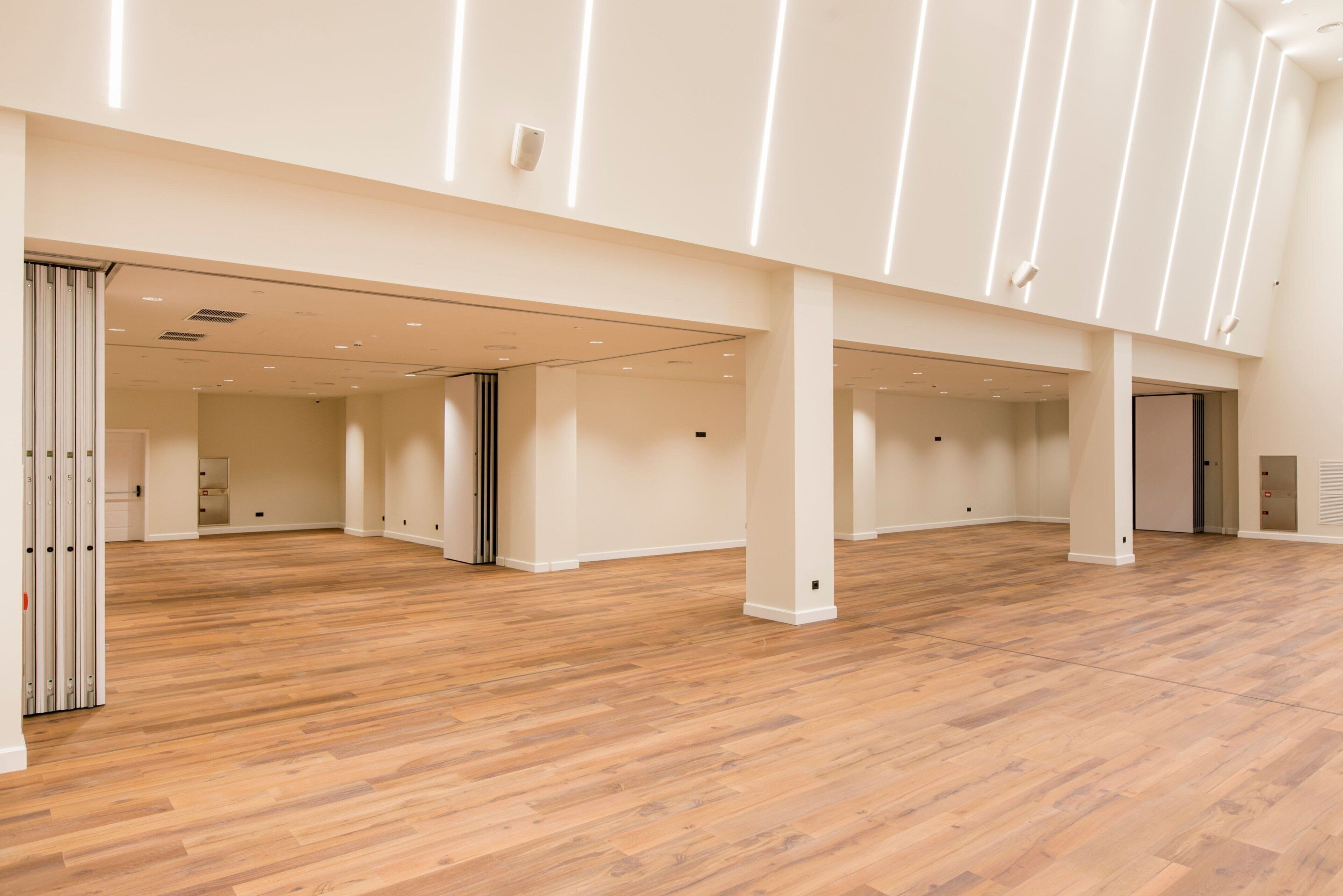 Un interior amplio, bien iluminado, con piso de madera y paredes blancas.