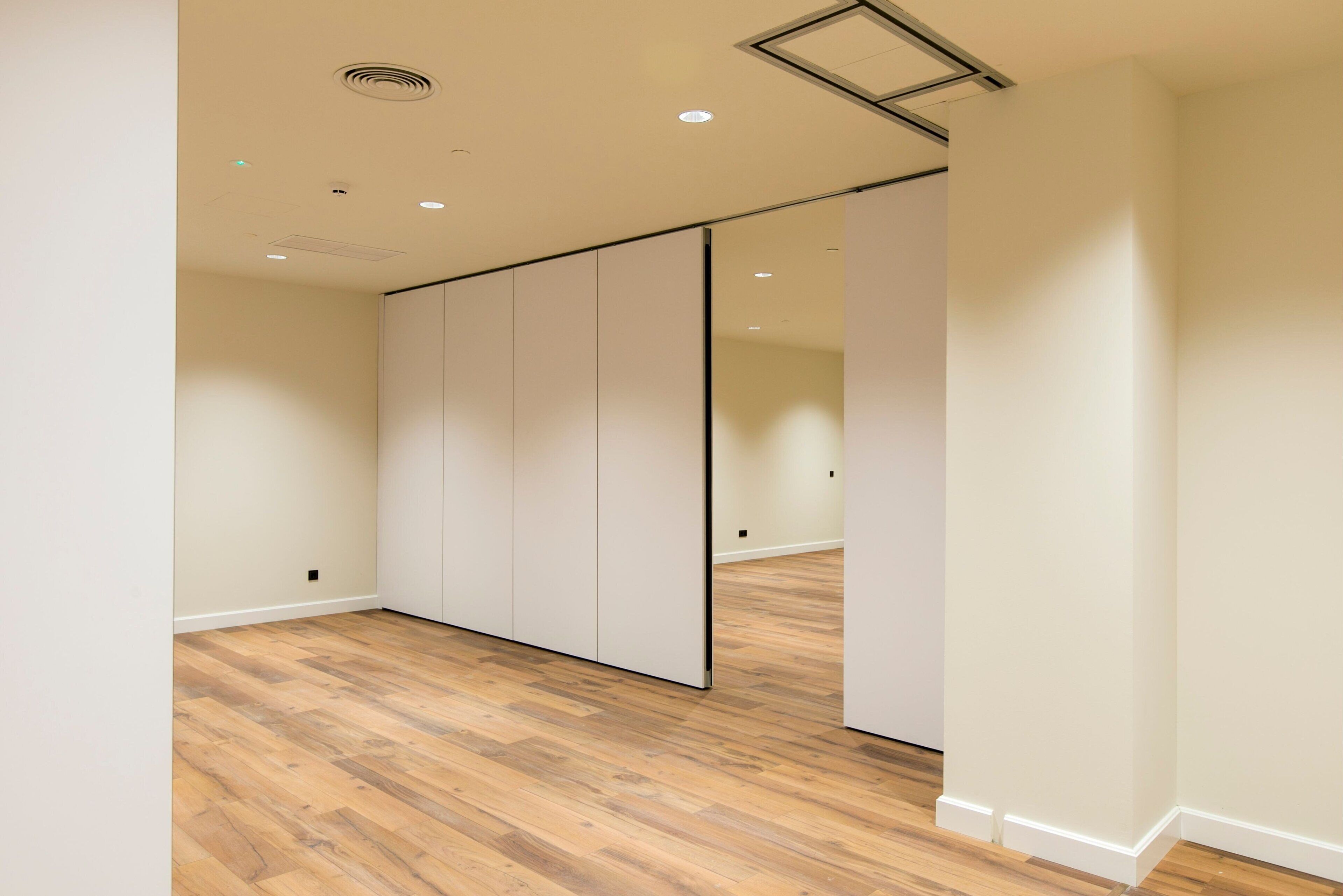 A room with a wooden floor, white walls, and a sliding door.