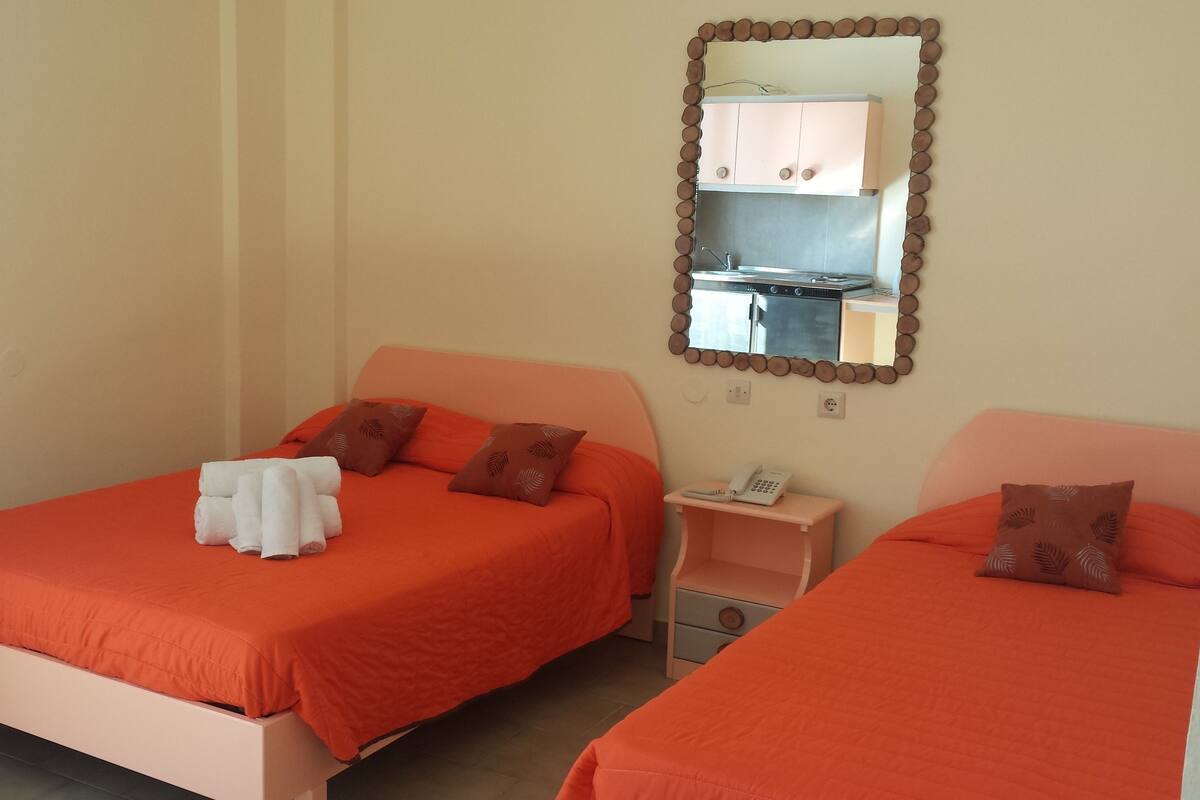 A hotel room with two beds, a small bedside table with a phone, and a mirror above the bed.