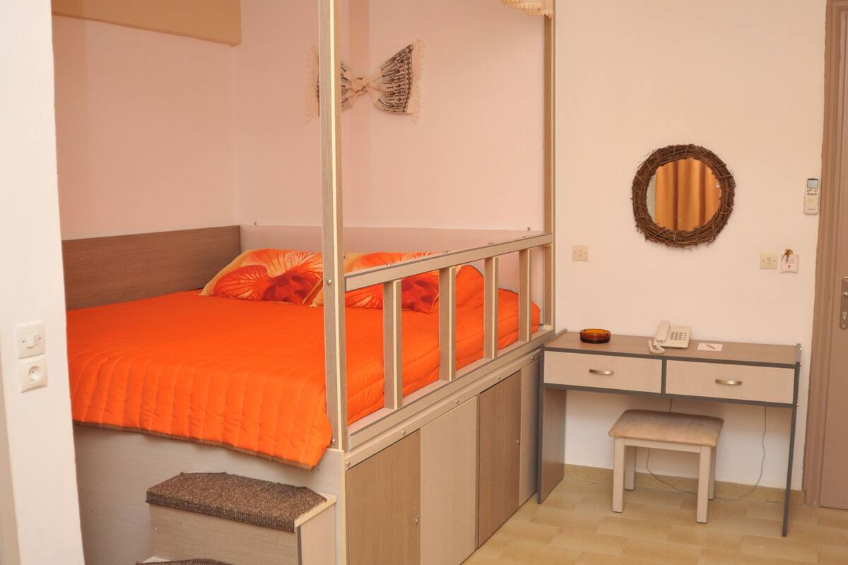 A compact room with a bunk bed, a desk with a chair, and a small stool.