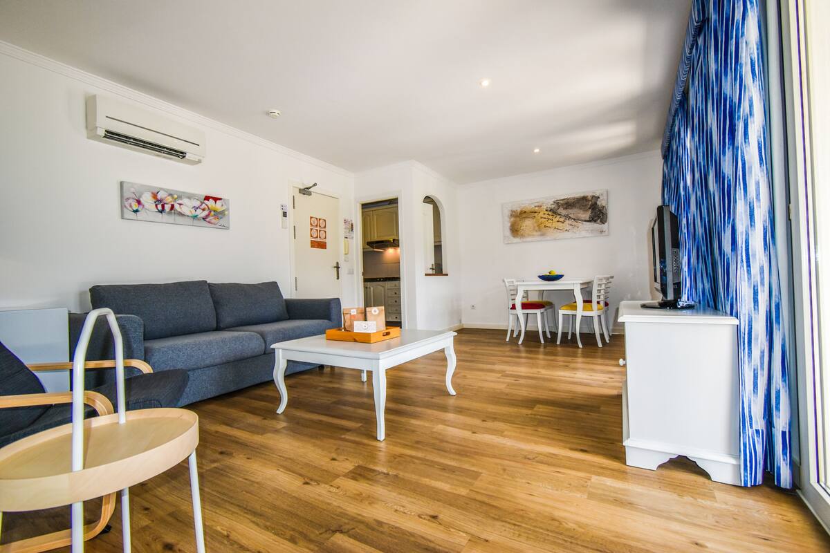 A modern living room with a grey sofa, white coffee table, and wooden flooring.
