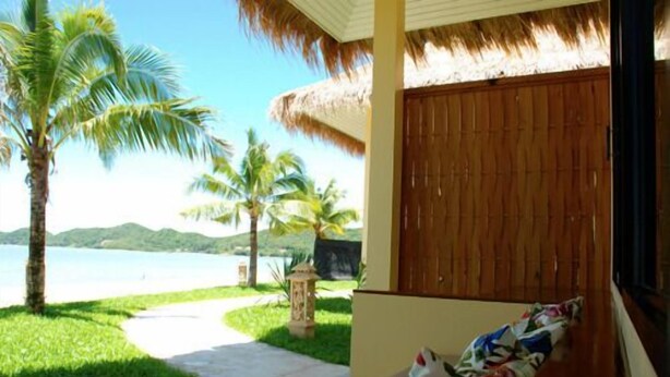 Una habitación con vista a la playa, techo de paja y puerta de madera.