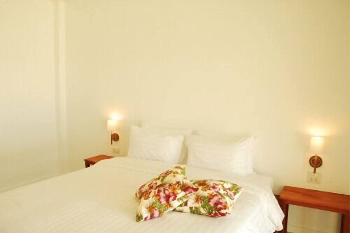 A neatly made bed with floral pillows and two bedside lamps.