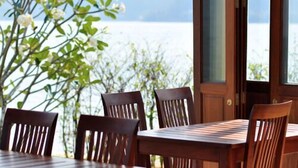 Una mesa y sillas de madera con vistas a un lago y montañas a través de un ventanal.