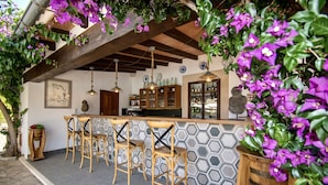 A bar area with wooden chairs, a hexagonal tiled wall, and hanging pendant lights.