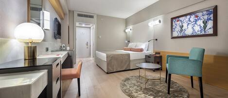 Una habitación de hotel moderna con una cama, un escritorio, una silla y una pequeña mesa. Hay un cuadro en la pared y una alfombra en el suelo.