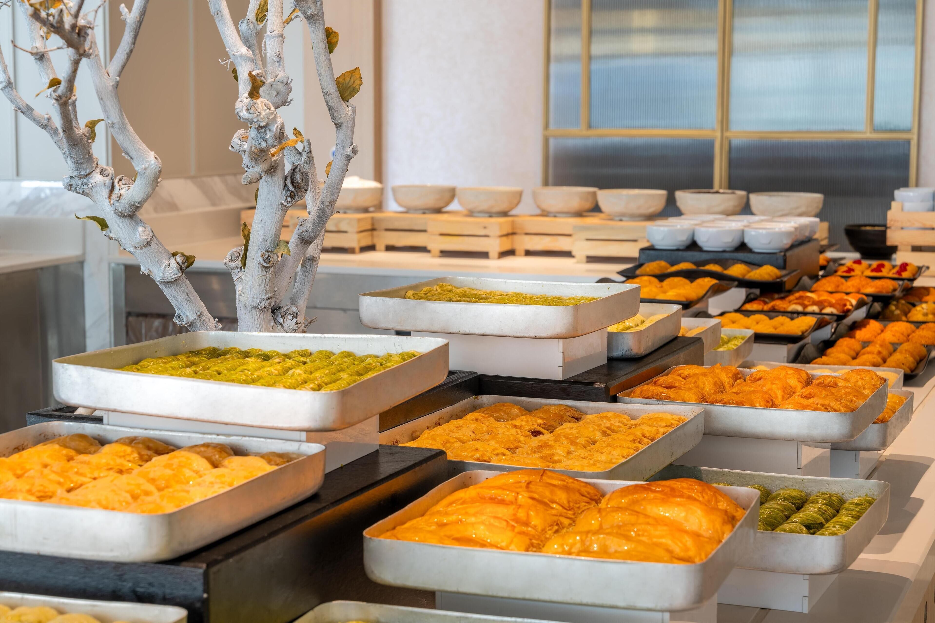 A buffet with various dishes in trays, including pastries and salads.
