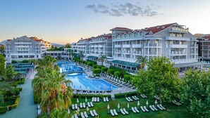 Un resort con varias edificaciones, una piscina central y tumbonas.