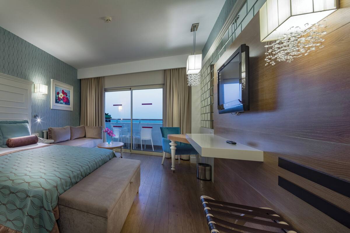 Una habitación de hotel moderna con una cama grande, un escritorio y un balcón con vistas.