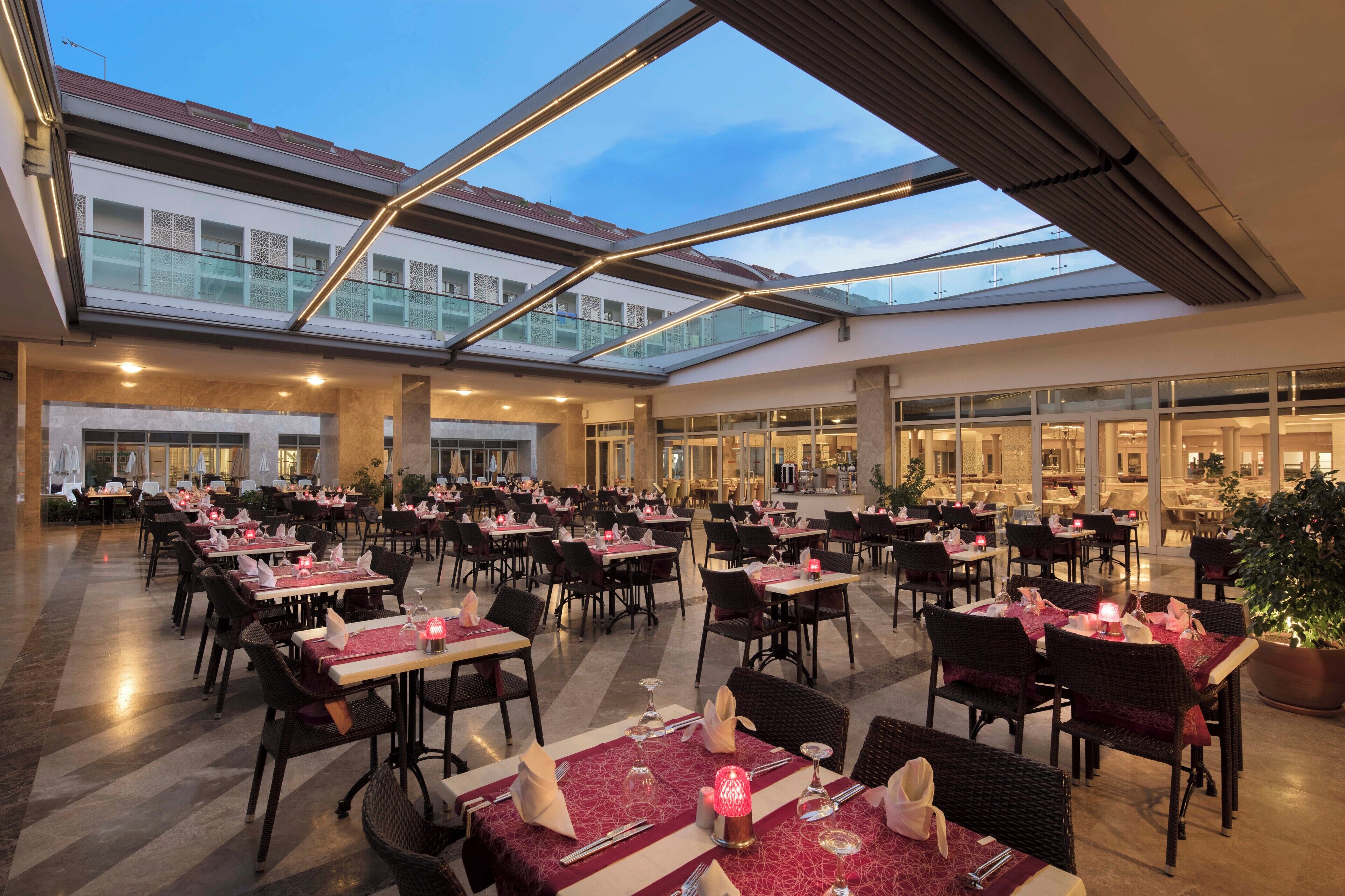 A spacious indoor dining area with multiple tables and chairs, large windows, and a modern architectural design.