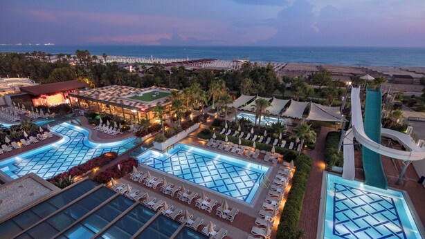 Ein Resort mit mehreren Schwimmbecken, Liegestühlen und Blick auf Strand und Meer.