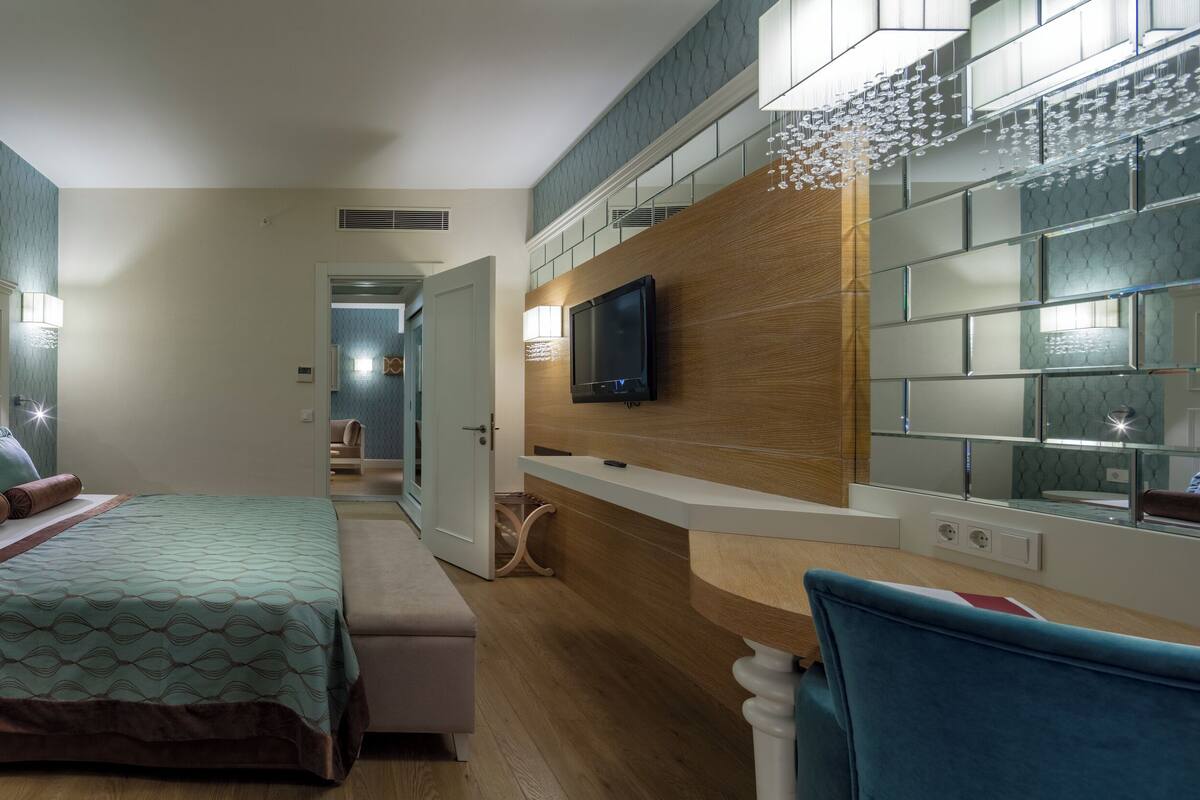 Una habitación de hotel con cama, mesita de noche y televisor en la pared.