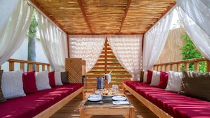 A covered outdoor seating area with wooden benches and a table set for dining. - Trendy Palm Beach (Adults Only, 16+) - All inclusive (Manavgat)