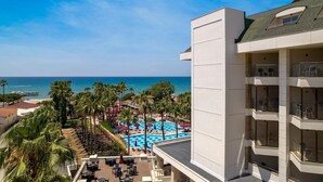 A hotel with a rooftop pool, palm trees, and a view of the beach and ocean. - Trendy Palm Beach (Adults Only, 16+) - All inclusive (Manavgat)