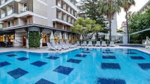 A hotel pool area with lounge chairs and umbrellas, surrounded by a multi-story building with balconies. - Trendy Side Beach (Adults Only, 16+) - All inclusive (Manavgat)