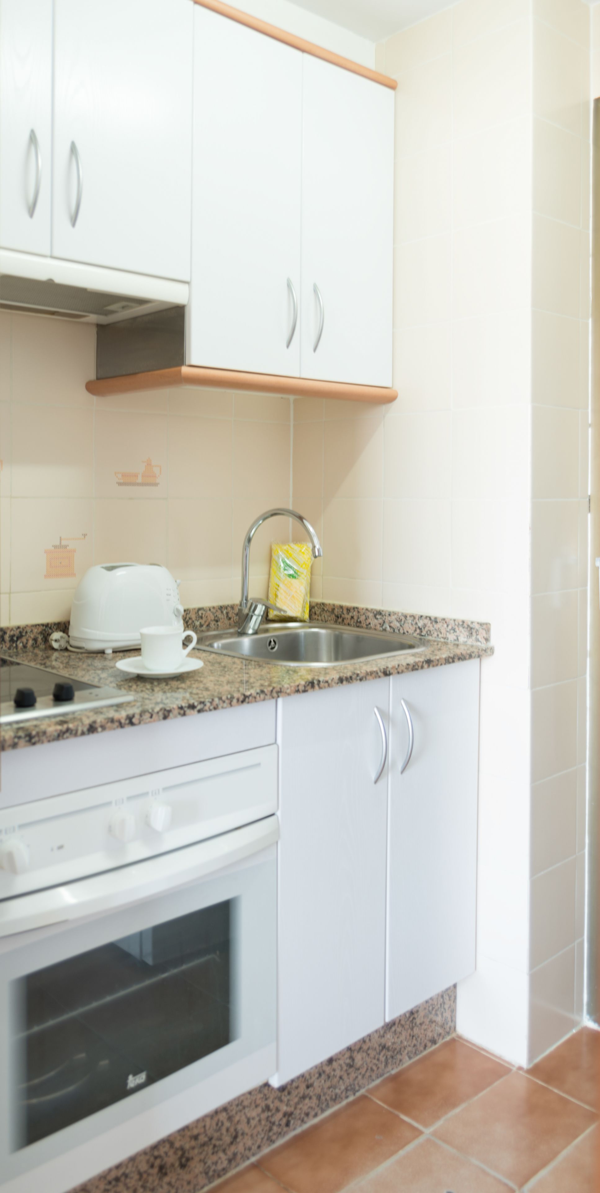 A kitchen with white cabinets, a granite countertop, a coffee maker, and a toaster.