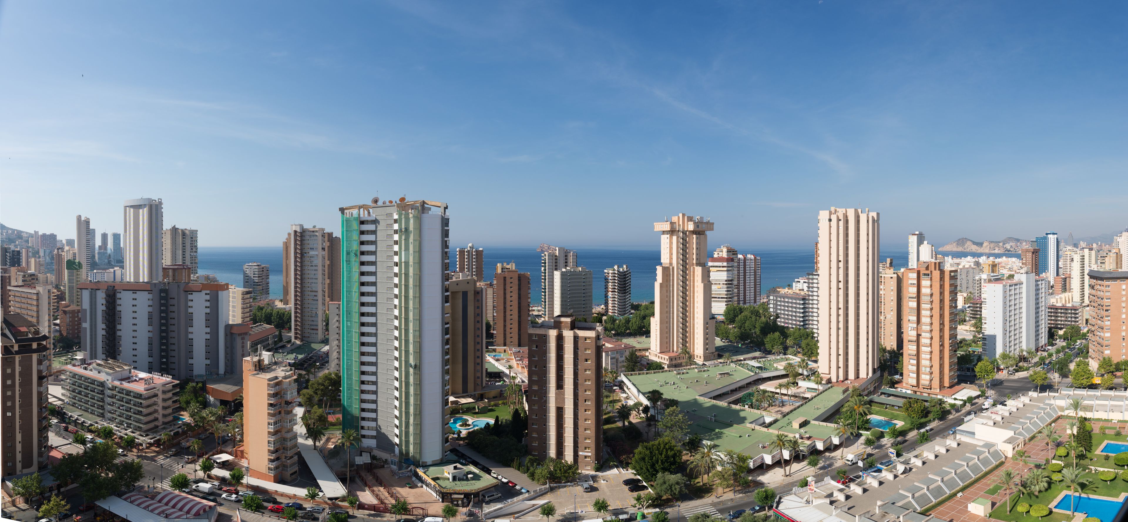 Un hôtel de grande hauteur, avec de nombreux étages, une piscine sur le toit et une vue panoramique sur la ville.
