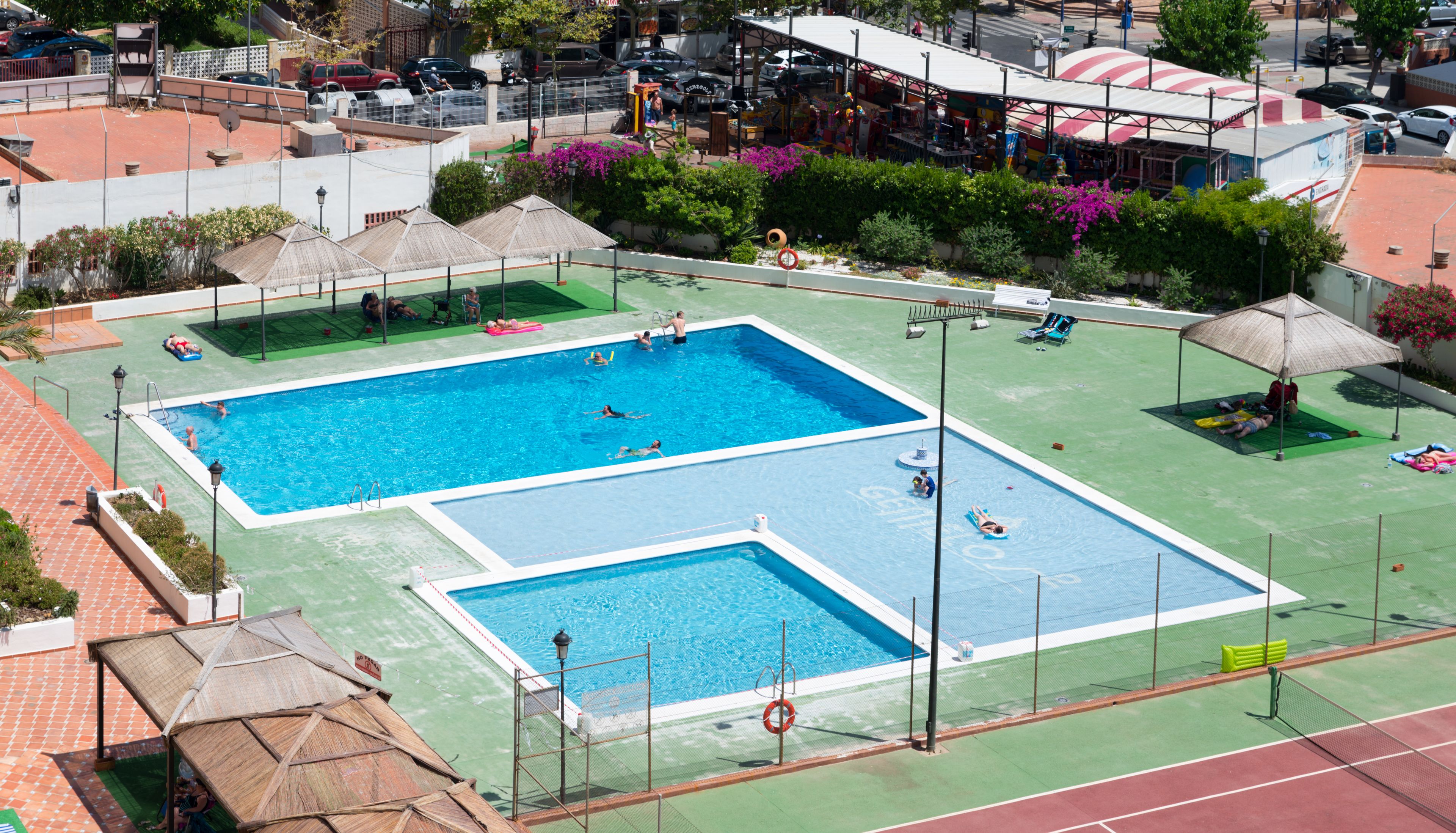 Una gran piscina al aire libre con varias pistas y una cancha de tenis.