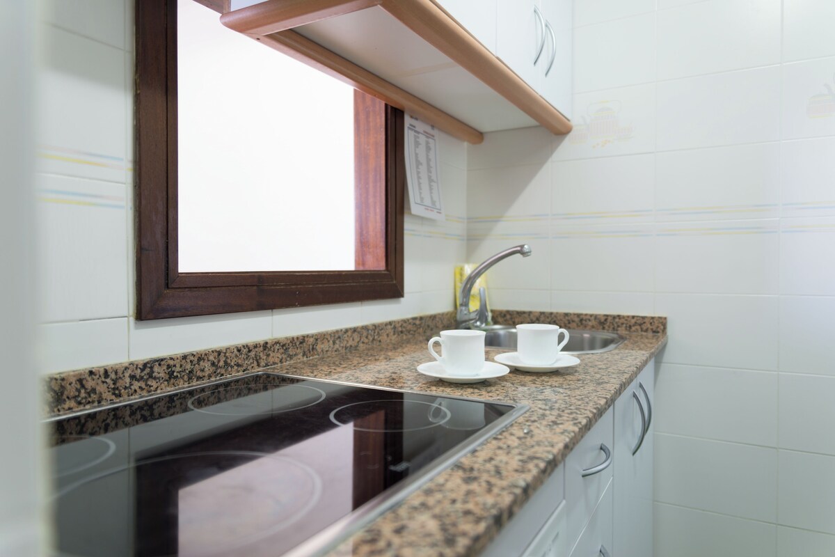 A kitchen with a built-in stovetop, a window, and a sink.