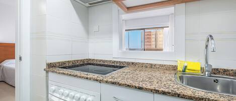 A kitchen with white cabinets, a granite countertop, a stainless steel sink, and a window above the sink.