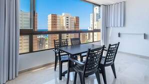 Una habitación con un ventanal grande, una mesa de comedor con sillas y vistas a rascacielos.