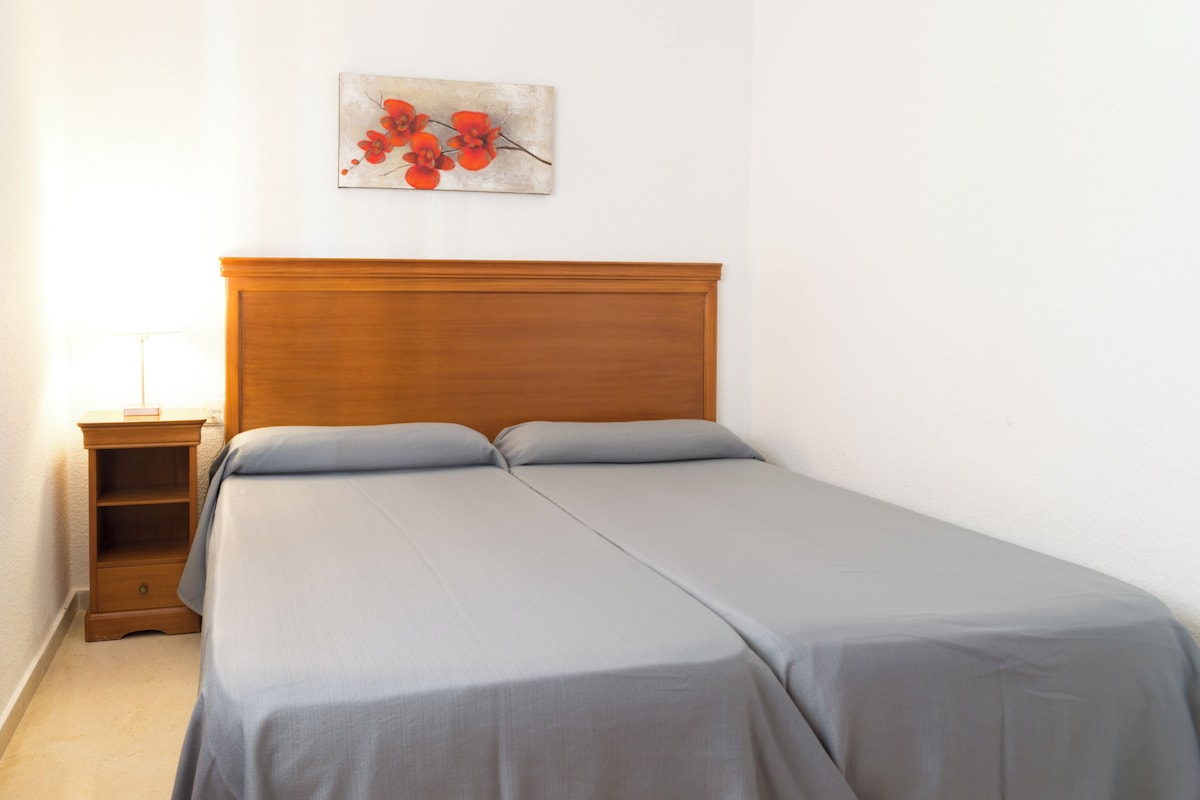 A single bed with a wooden headboard, a bedside table, and a wall-mounted artwork.