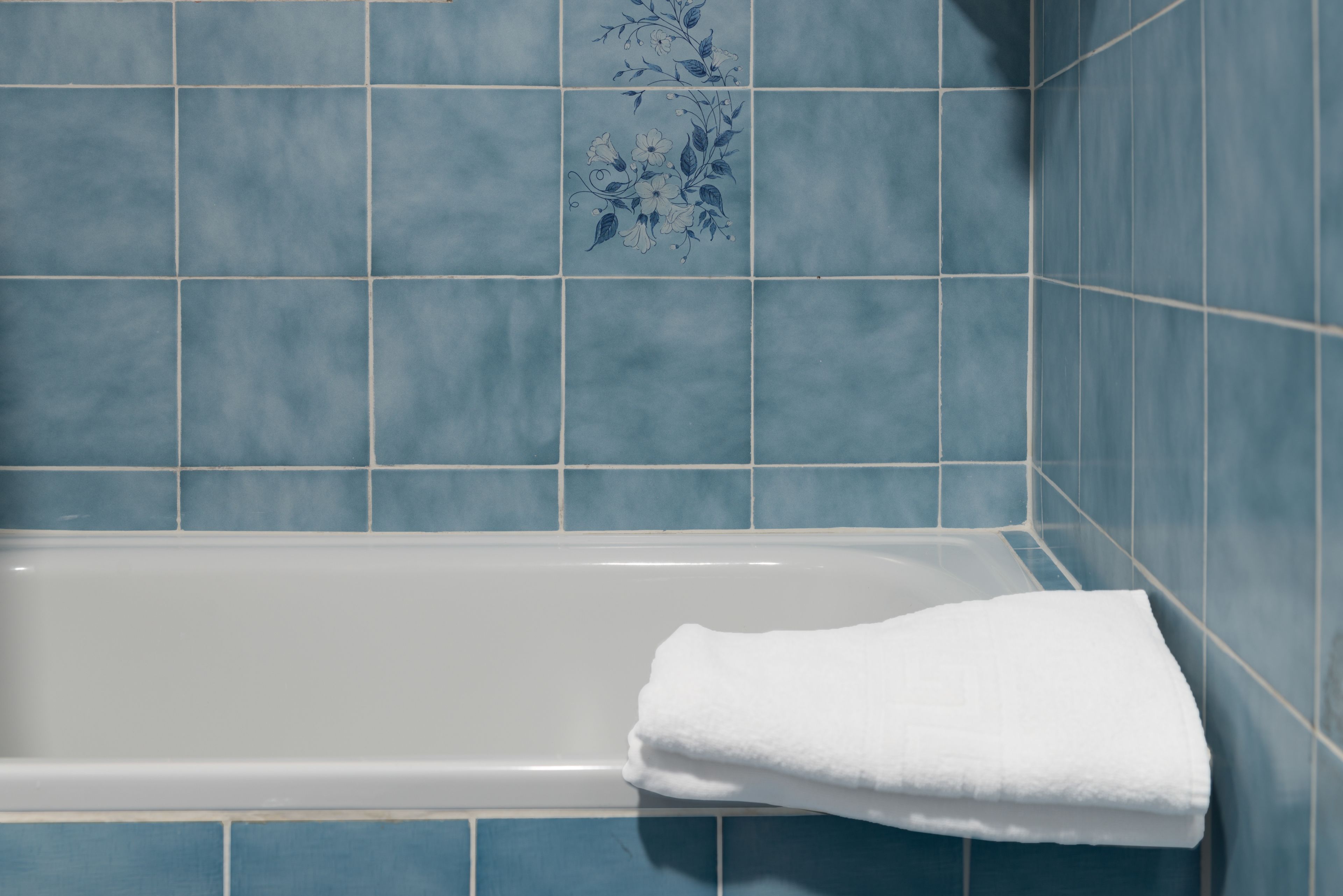 A bathroom with a bathtub and blue tiles.