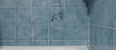 A bathroom with a bathtub and blue tiles.