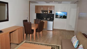 Un espace de vie compact comprenant un coin repas, une kitchenette et un canapé agrémenté de coussins colorés.