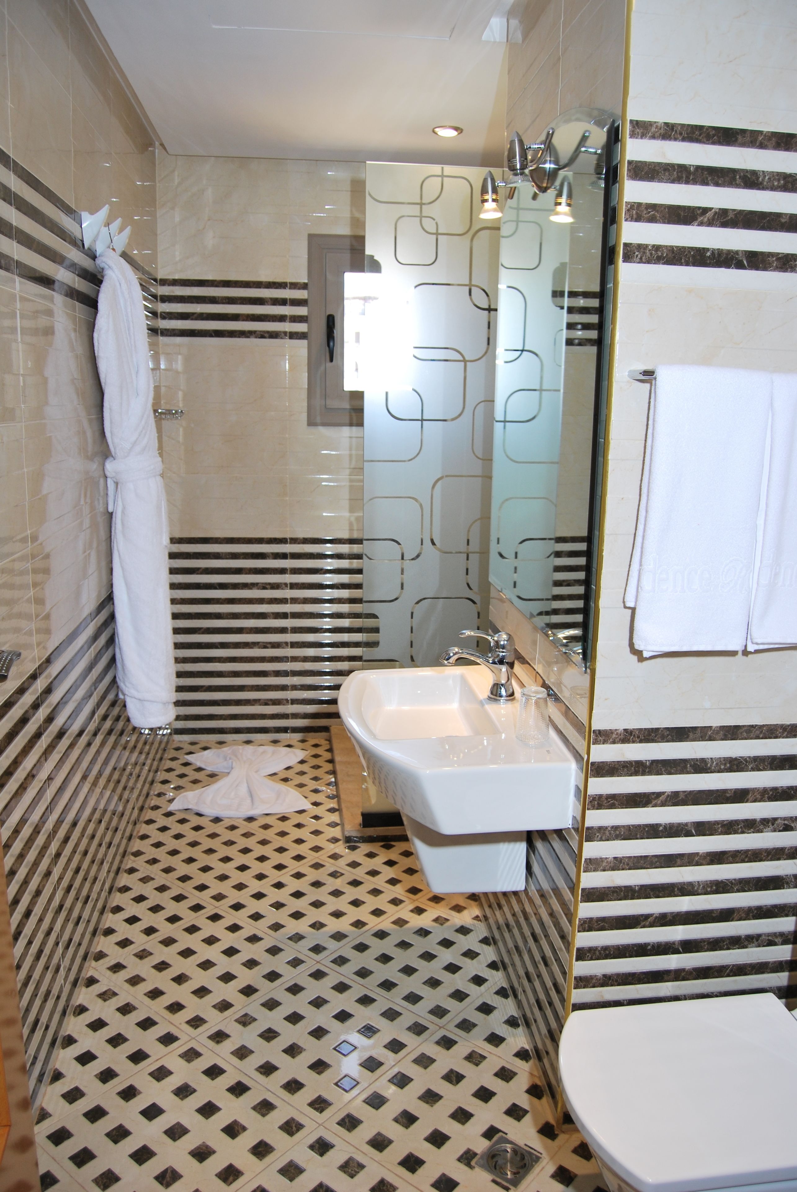 A bathroom with a sink, toilet, and a large mirror.