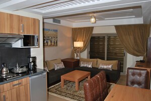 A compact living space with a kitchenette, a sofa set, a dining table, and a lamp.