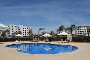 Piscine extérieure, parasols de plage, chaises longues
