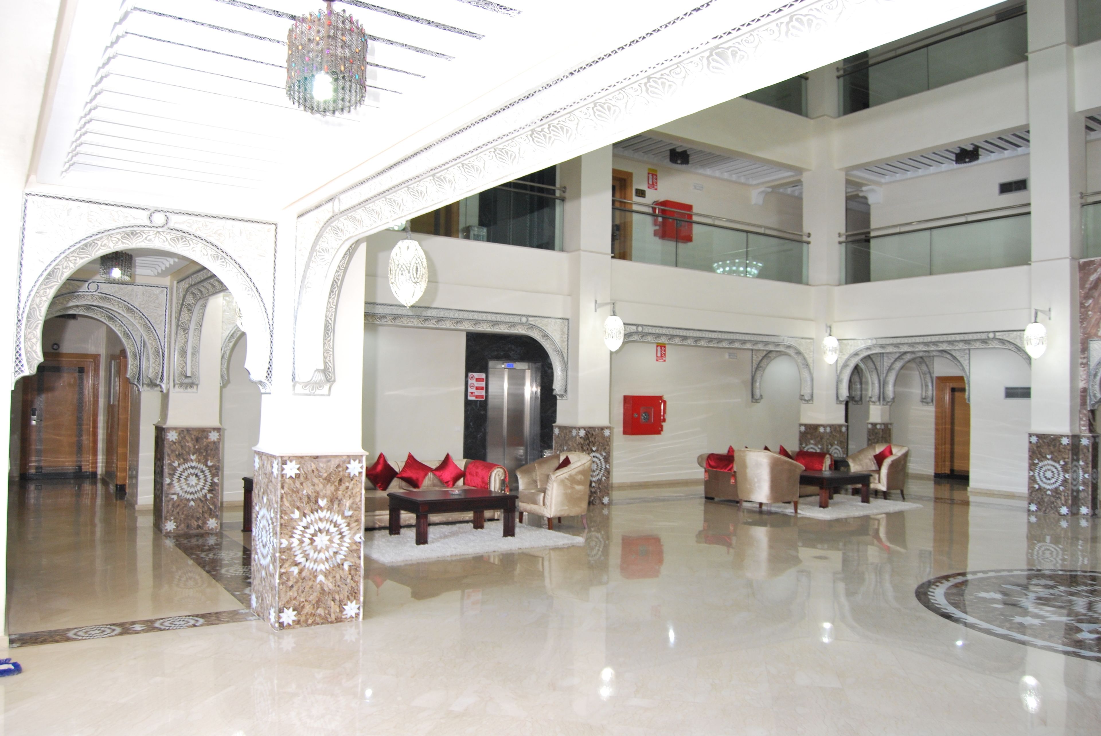 A spacious lobby with high ceilings, ornate columns, and a central seating area with sofas and armchairs.