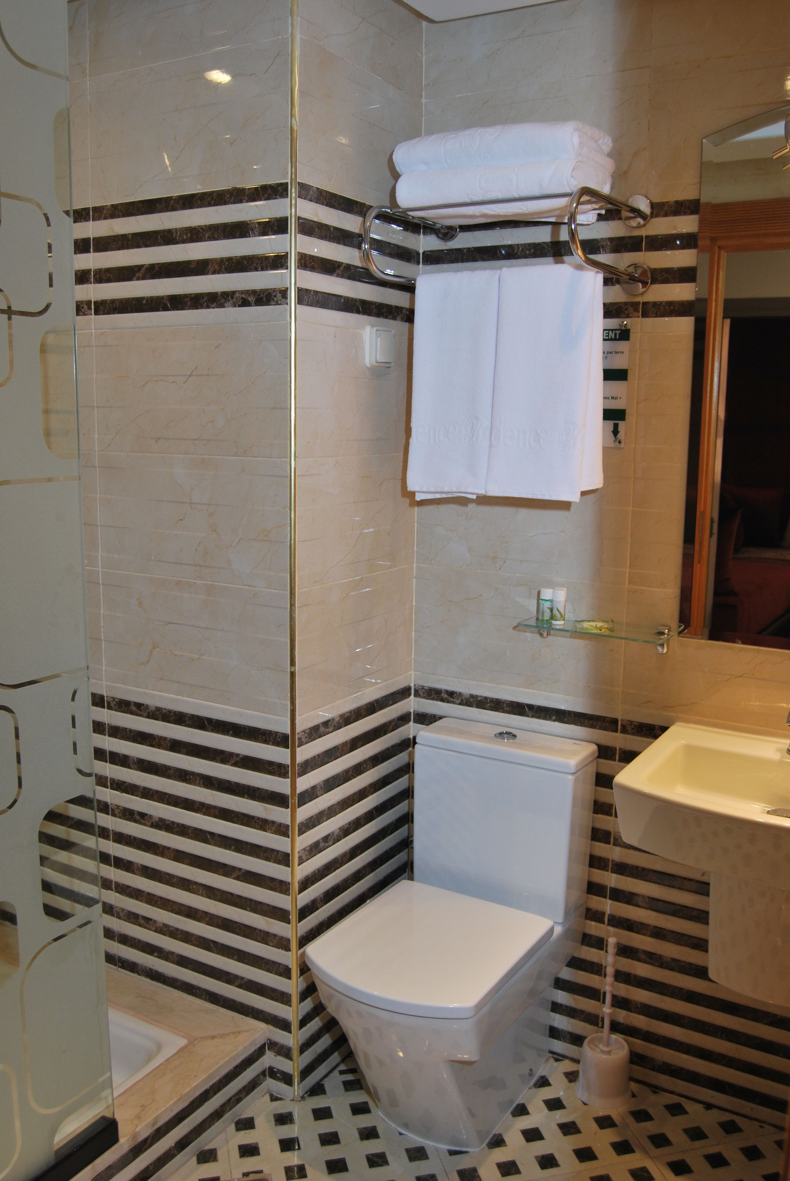 Un baño con ducha separada por mampara de vidrio, inodoro y lavamanos.