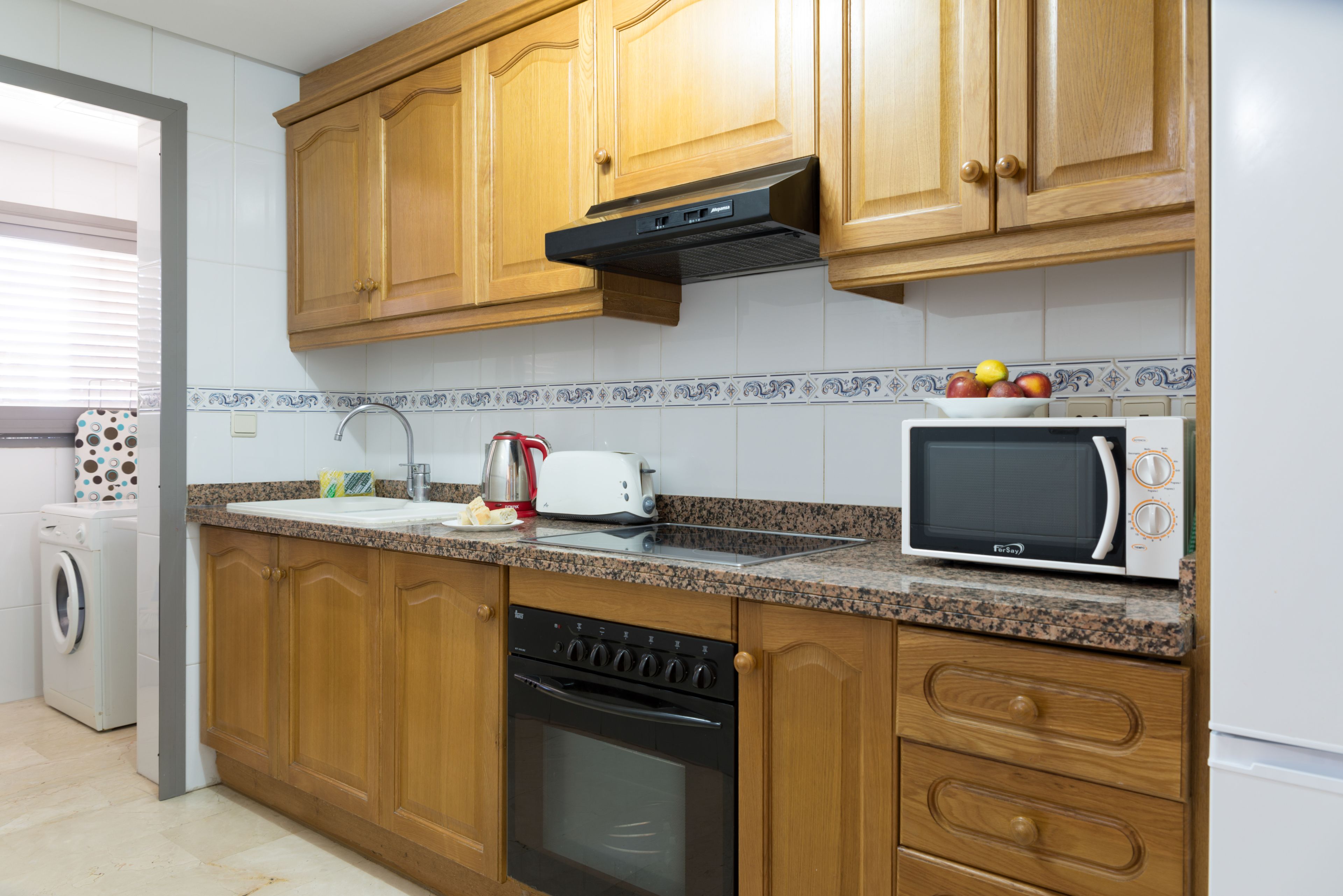 A kitchen with wooden cabinets, a built-in oven, a microwave, and a toaster.