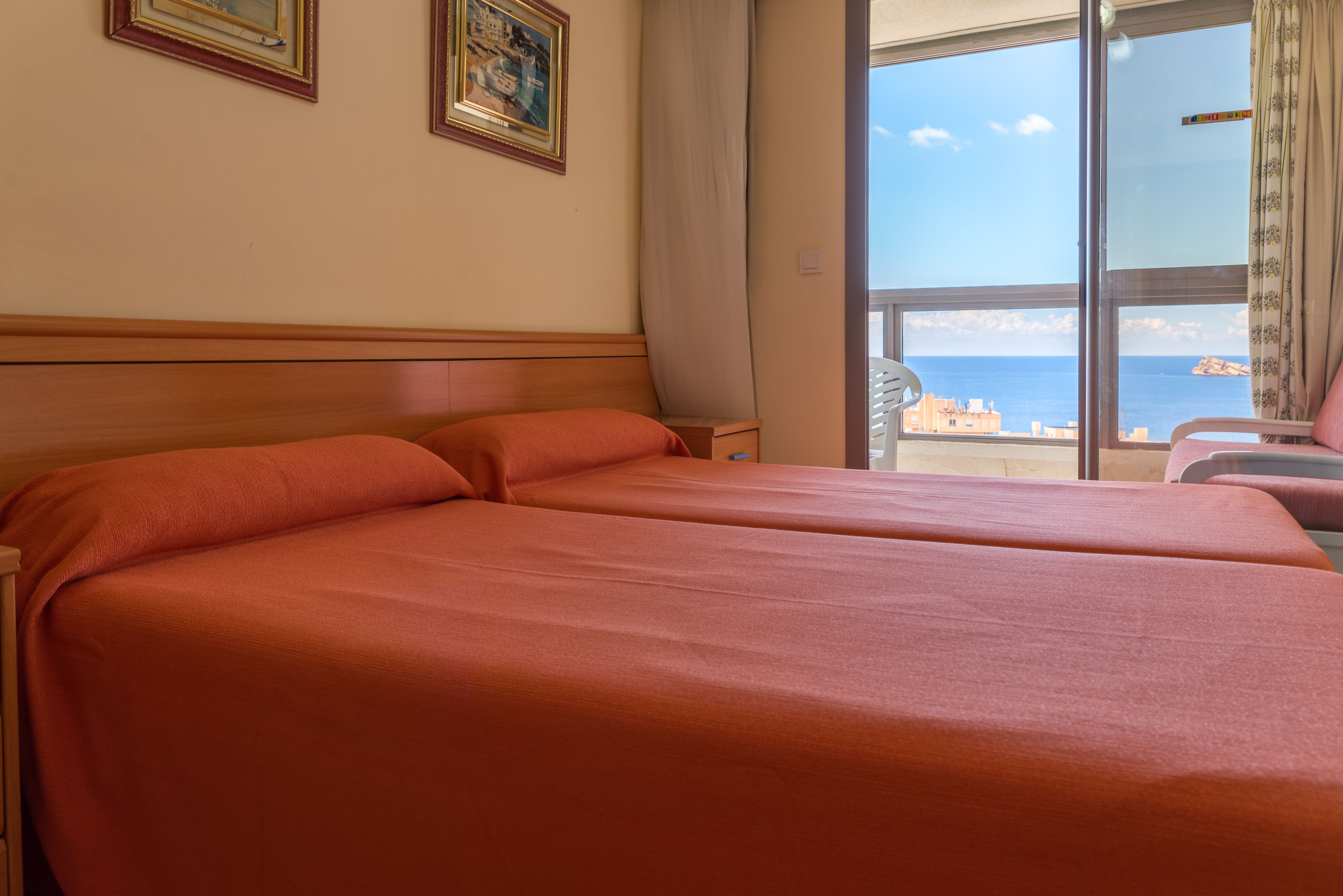 Habitación de hotel con una cama grande, vistas al mar y dos cuadros en la pared.