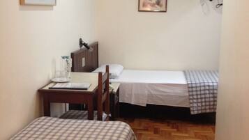 A hotel room with two beds, a desk, a chair, a television, and two framed pictures on the wall.